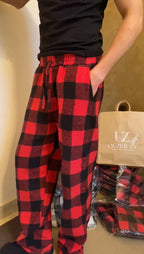 Person wearing red and black plaid pants with a beige bag in the background.
